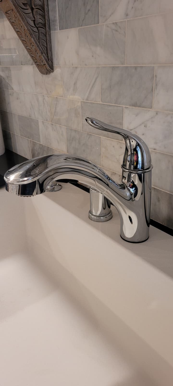 Polished chrome bathroom faucet against marble tile