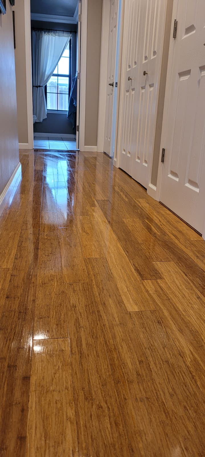 Polished wood hallway floor reflecting ceiling light
