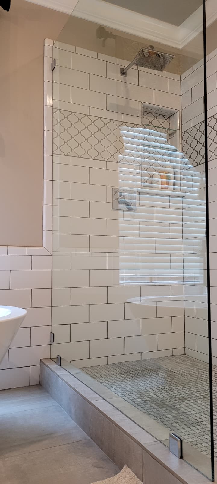 Spotless glass shower with white tile and niche